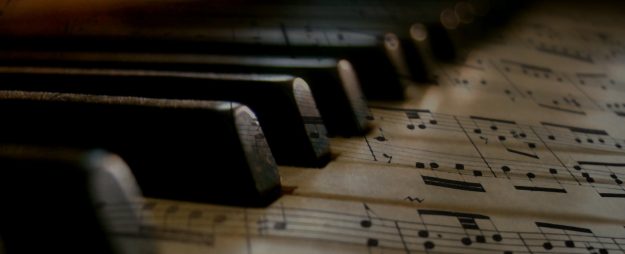musiikkiopisto12 Taiteellinen kuva pianon koskettimista nuottipaperin kera.